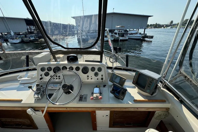 Slide: The Image of 1985 Silverton 40 Aft Cabin helm with steering wheel, gauges, and navigation equipment at marina. - 6