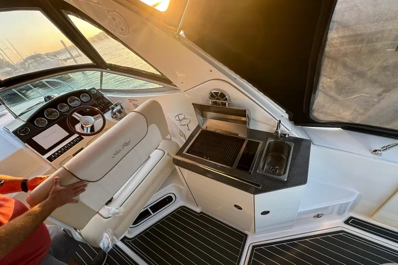 Slide: The Image of 2012 Sea Ray Sundancer 310 cockpit with helm, grill, and sink at sunset. - 12