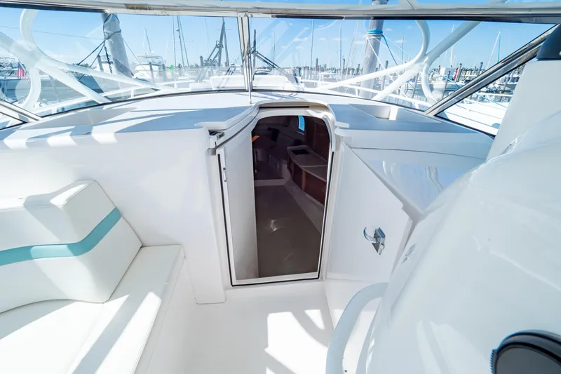 Slide: The Image of 2018 Intrepid 475 Sport Yacht interior with open cabin door, white seating, and marina view. - 119