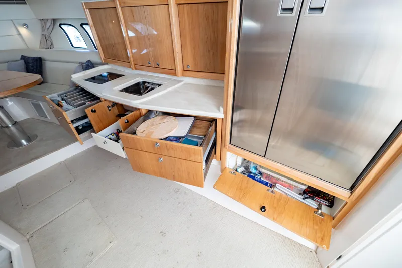 Slide: The Image of 2018 Intrepid 475 Sport Yacht interior kitchen with open cabinets and stainless steel appliances. - 139