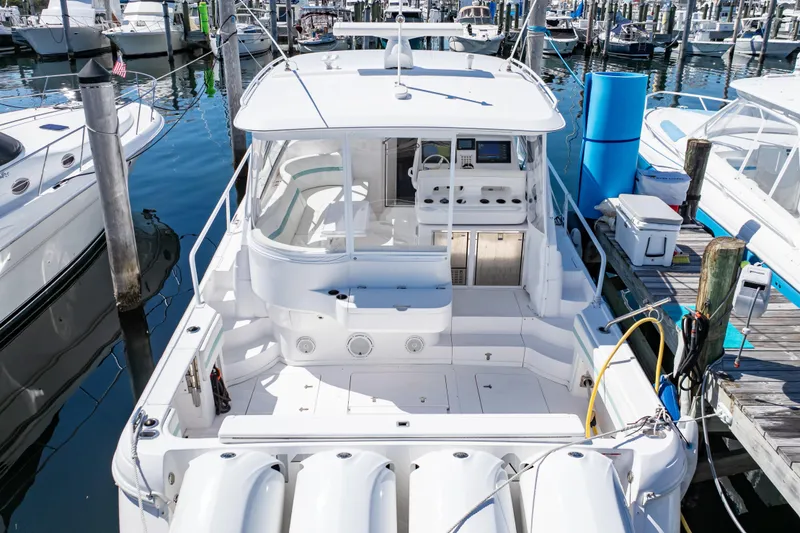 Slide: The Image of 2018 Intrepid 475 Sport Yacht docked at marina, showcasing spacious deck and sleek design. - 18