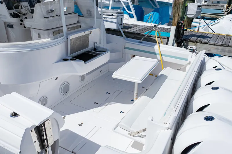 Slide: The Image of 2018 Intrepid 475 Sport Yacht deck with seating, table, and sink at marina. - 7