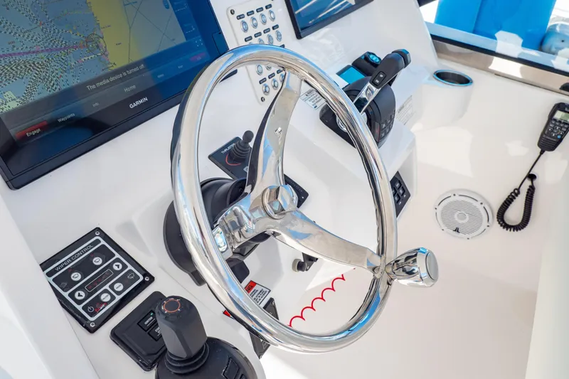 Slide: The Image of 2018 Intrepid 475 Sport Yacht helm with steering wheel and navigation controls. - 95