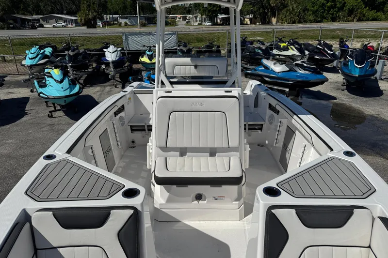 Slide: The Image of 2025 Yamaha Boats 222 FSH Sport interior with seating and storage, surrounded by jet skis. - 12