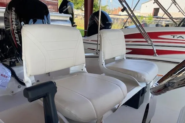 Slide: The Image of 2026 Boston Whaler 130 Super Sport boat interior with white cushioned seats and Mercury engine. - 2