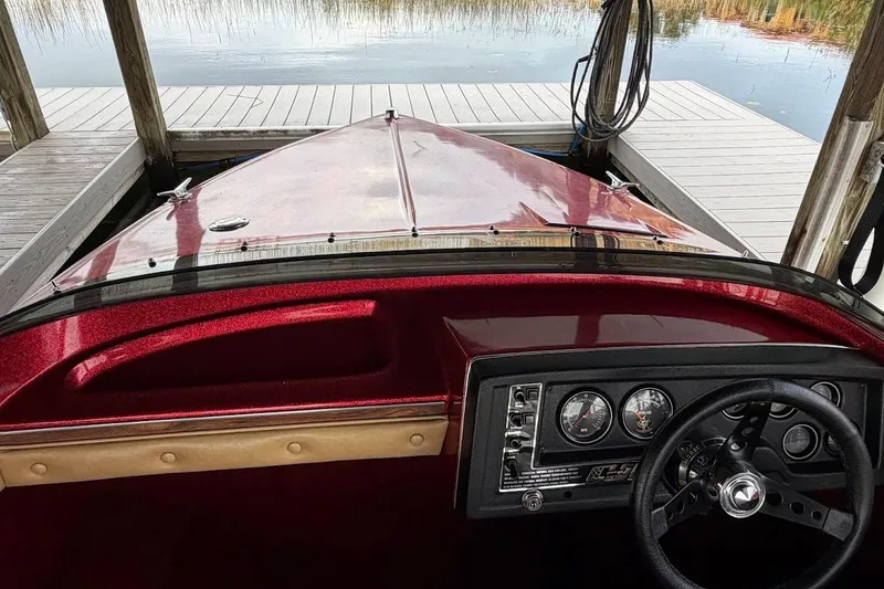 Slide: The Image of 1981 Glastron/Carlson C512 boat dashboard with steering wheel, docked by a serene lake. - 34
