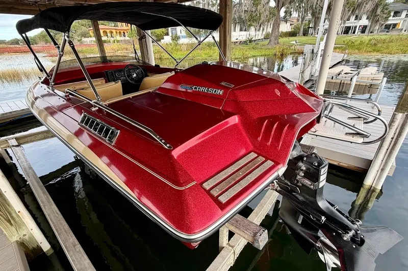 Slide: The Image of 1981 Glastron/Carlson C512 boat with red exterior, docked on a serene lake. - 6