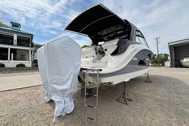 Slide: The Image of 2026 Sea Ray Sundancer 370 Outboard boat with covered engines, parked on gravel. - 2