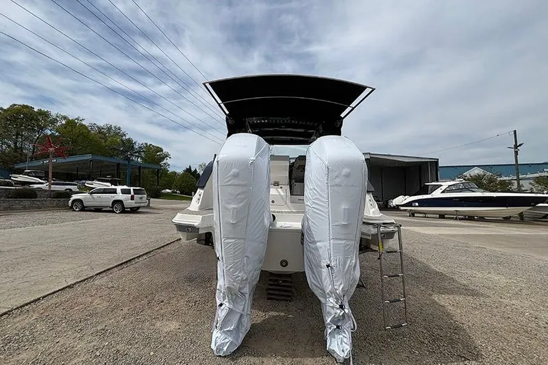 Slide: The Image of 2026 Sea Ray Sundancer 370 Outboard with covered engines, parked outdoors. - 3