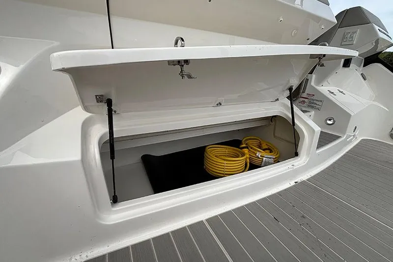 Slide: The Image of Open storage compartment on 2026 Sea Ray Sundancer 370 Outboard with coiled yellow hose. - 4