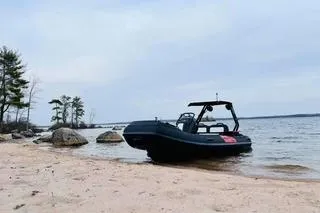 Slide: The Image of 2025 Highfield Velox 420 boat on a sandy beach with a scenic lake view. - 2
