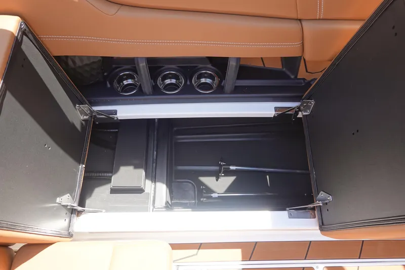 Slide: The Image of 2026 Malibu Wakesetter 21 LX storage compartment with open hatches and cup holders. - 25