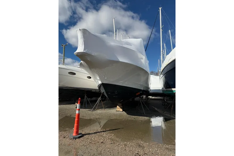 The Image of 1997 Silverton 442 Cockpit Motor Yacht covered in protective wrap, parked on dry land. - 1
