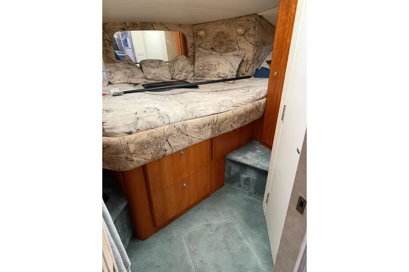 Slide: The Image of 1997 Silverton 442 Cockpit Motor Yacht cabin with patterned bedding and wooden storage drawers. - 14