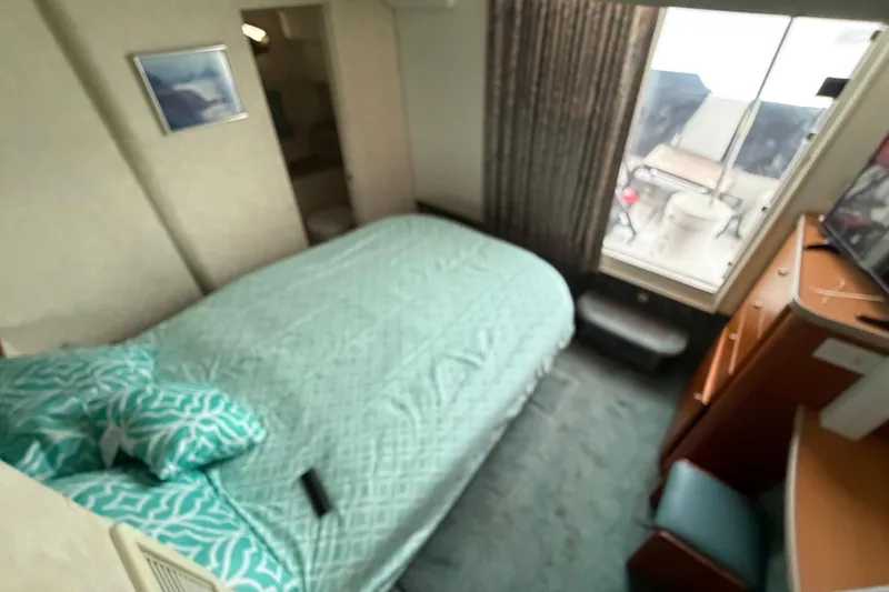 Slide: The Image of Cozy bedroom in 1997 Silverton 442 Cockpit Motor Yacht with teal bedding and window view. - 20