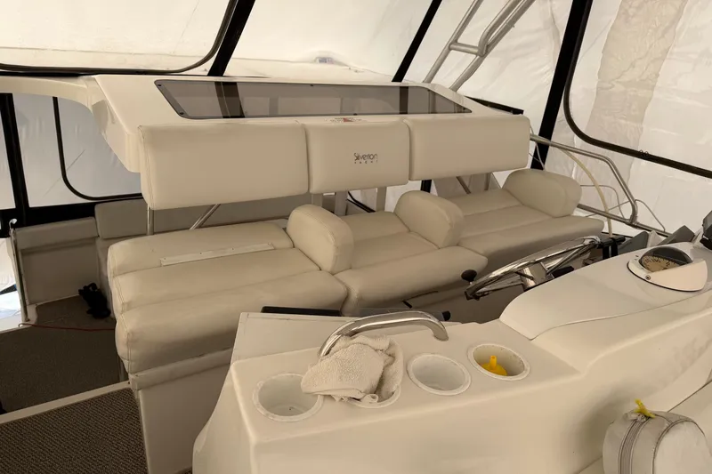 Slide: The Image of 1997 Silverton 442 Cockpit Motor Yacht interior with white seating and helm station. - 38