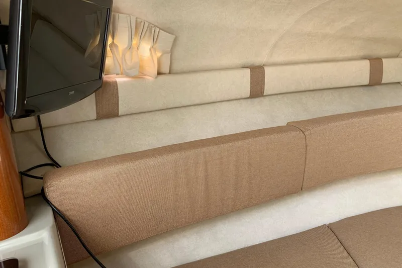 Slide: The Image of Interior of 2011 Sea Ray 240 Sundancer with beige seating and mounted TV. - 17