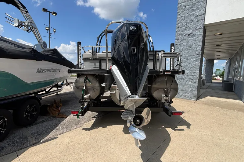 Slide: The Image of 2023 Princecraft Quorum 25 RL pontoon boat, rear view with motor, parked outdoors. - 6