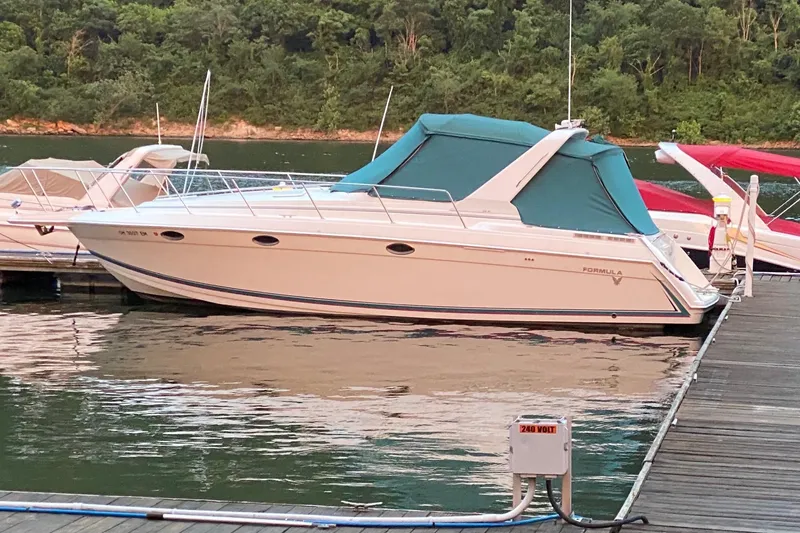The Image of 1997 Formula 34 Performance Cruiser docked on a serene lake with lush greenery. - 1
