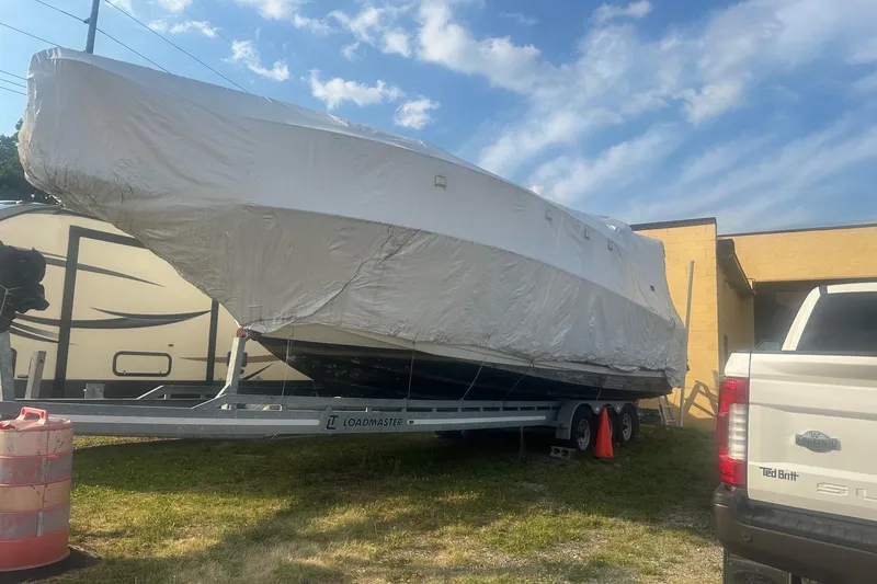 Slide: The Image of 1997 Formula 34 Performance Cruiser covered on trailer, parked outdoors under blue sky. - 15
