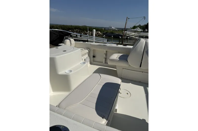Slide: The Image of 2004 Hydra-Sports Lightning 202 DC boat interior with seating and storage, docked by the water. - 9