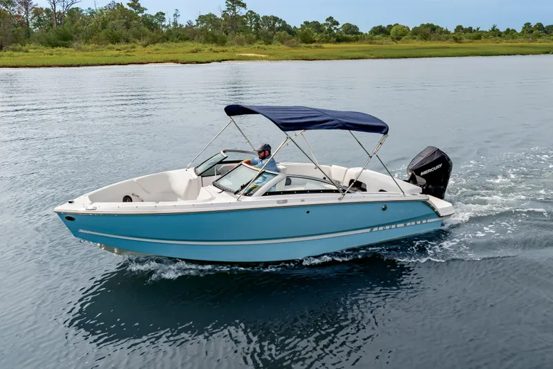 Slide: The Image of 2026 Four Winns H1 OB boat cruising on a serene lake with lush greenery. - 2