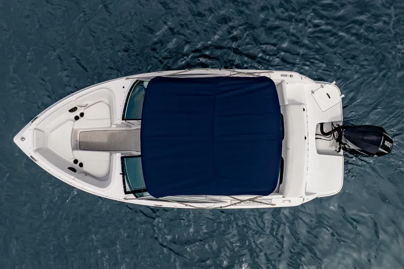 Slide: The Image of 2026 Four Winns H1 OB boat with blue cover, aerial view on water. - 10