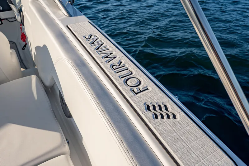 Slide: The Image of 2026 Four Winns H1 OB boat interior detail with logo, on calm water. - 14
