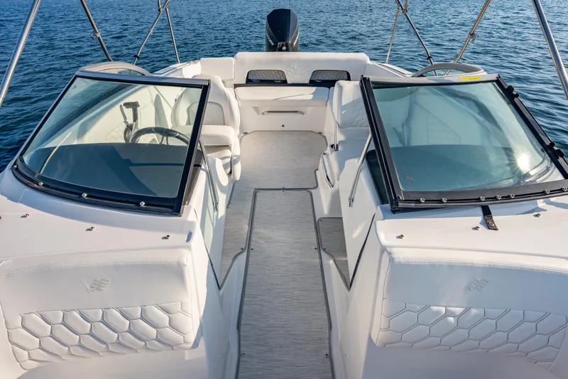 Slide: The Image of 2026 Four Winns H1 OB boat interior with dual windshields and seating, on calm water. - 15