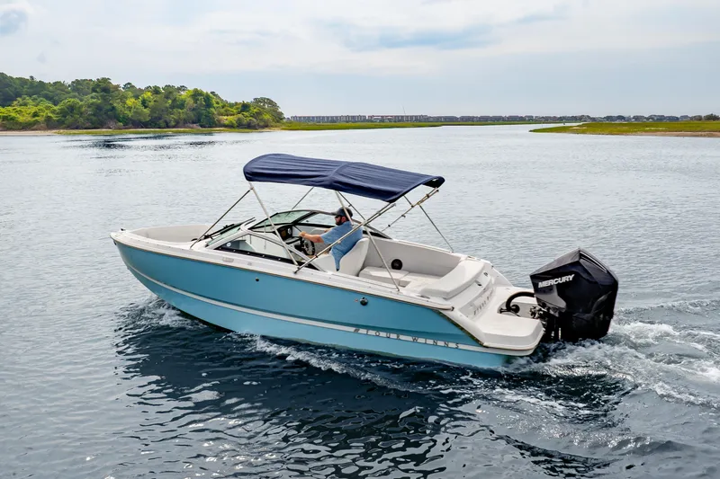 Slide: The Image of 2026 Four Winns H1 OB boat cruising on a scenic lake with lush greenery. - 4