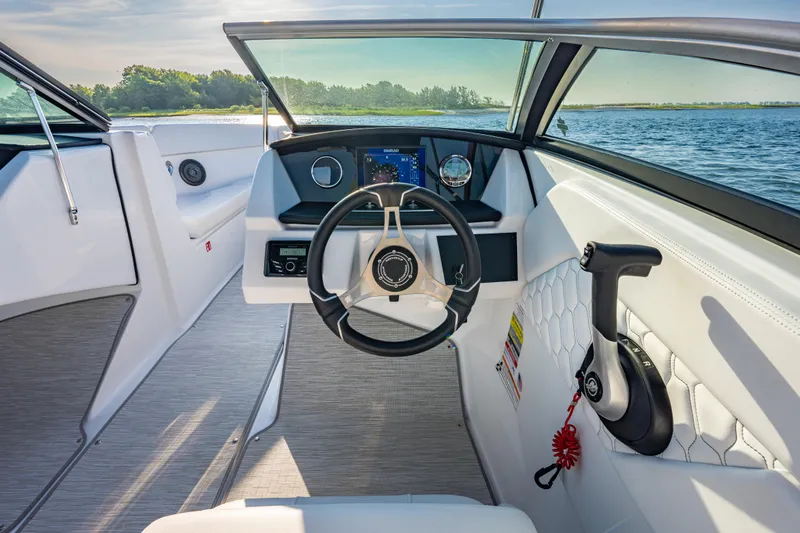 Slide: The Image of 2026 Four Winns H1 OB boat interior with modern steering and dashboard, overlooking serene water. - 17