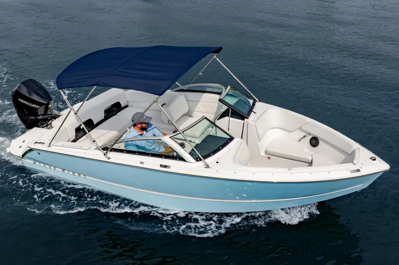 Slide: The Image of 2026 Four Winns H1 OB boat cruising on water with blue canopy and Mercury outboard motor. - 6