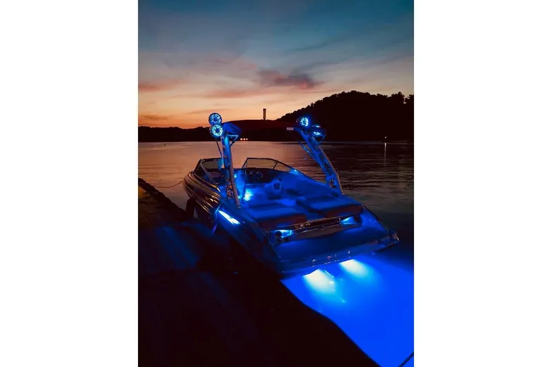 Slide: The Image of 2020 Crownline 235 SS boat with blue lights at sunset on a lake. - 11
