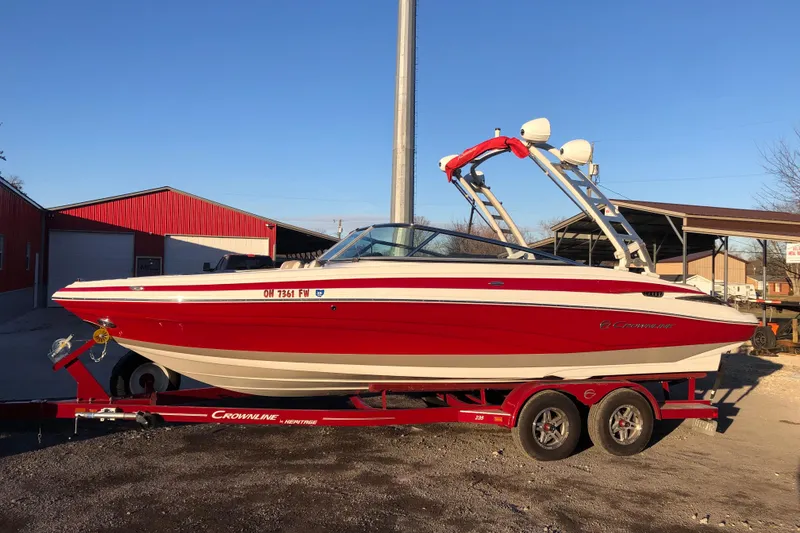 Slide: The Image of 2020 Crownline 235 SS boat in red on a trailer, parked outdoors. - 12
