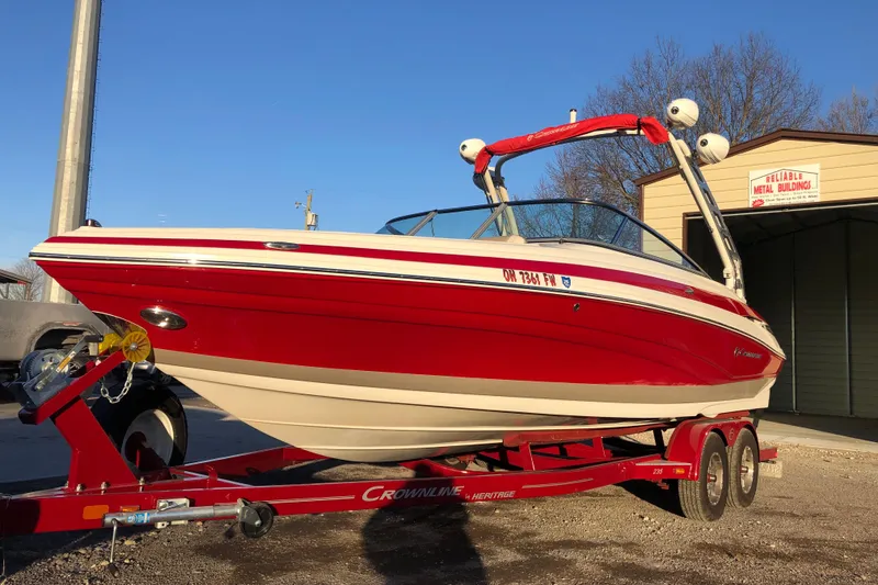 Slide: The Image of 2020 Crownline 235 SS boat on trailer, vibrant red color, parked outdoors. - 13