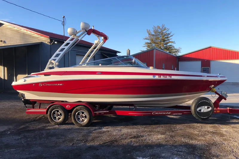 Slide: The Image of 2020 Crownline 235 SS boat in red on a trailer, parked near buildings. - 16