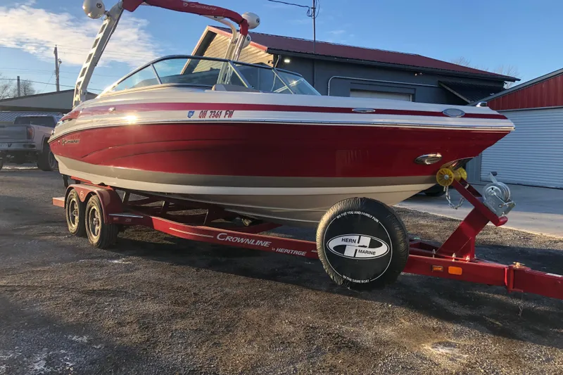 Slide: The Image of 2020 Crownline 235 SS boat on trailer, red and white, parked outdoors. - 17