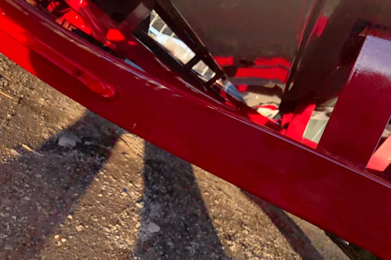 Slide: The Image of Close-up of a red 2020 Crownline 235 SS boat hull on gravel. - 24