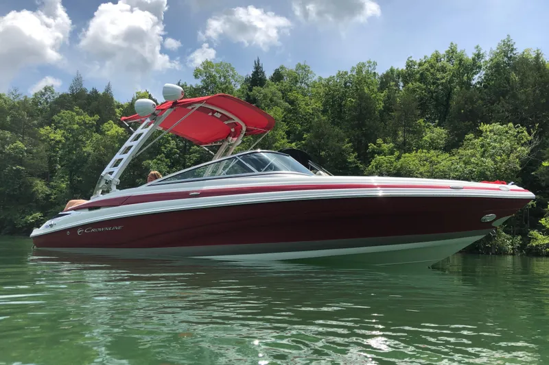 Slide: The Image of 2020 Crownline 235 SS boat on a serene lake with lush green trees. - 4