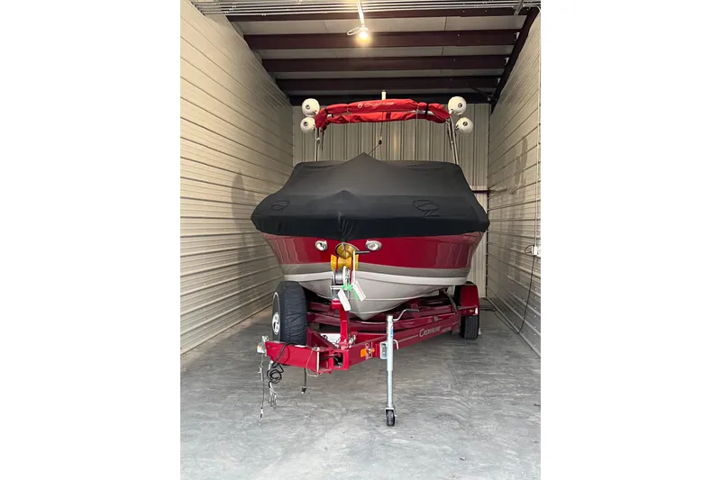 Slide: The Image of 2020 Crownline 235 SS boat in storage, covered and on a red trailer. - 6