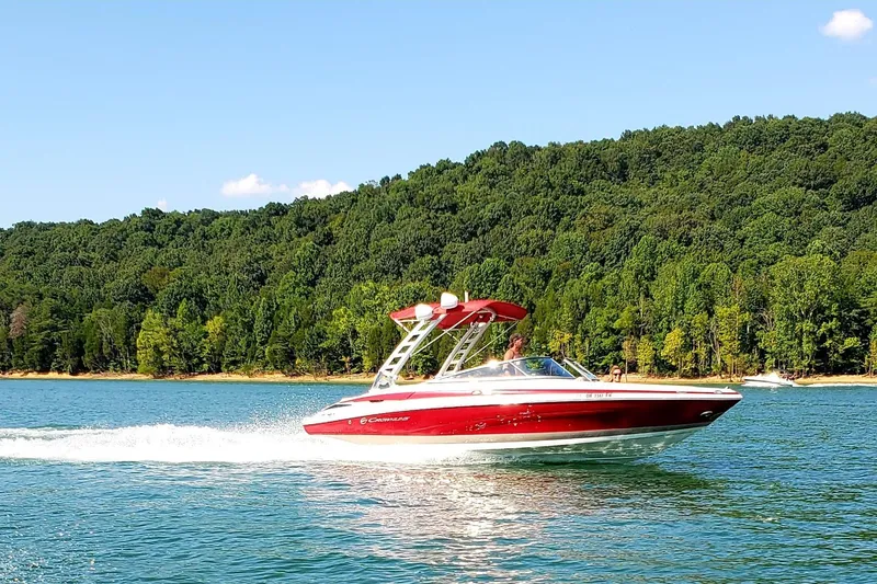 Slide: The Image of 2020 Crownline 235 SS boat cruising on a lake with forested shoreline. - 7