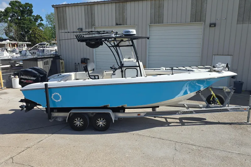 Slide: The Image of 2006 Fountain 23 Center Console boat on trailer, blue hull, parked outside a building. - 2