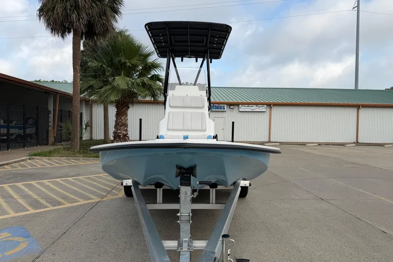 Slide: The Image of 2026 Shallow Sport 22 Sport boat on trailer, parked near palm trees and building. - 2