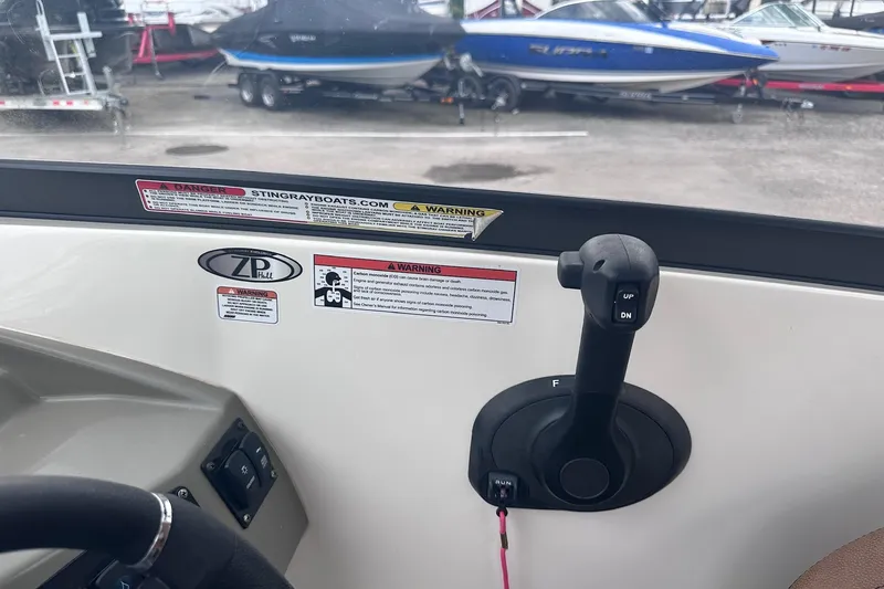 Slide: The Image of Control panel of a 2022 Stingray 201 DC boat with throttle lever and warning labels. - 14
