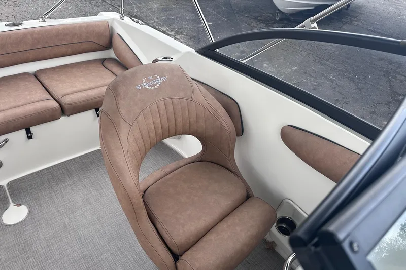 Slide: The Image of 2022 Stingray 201 DC boat interior with brown cushioned seating and steering area. - 15