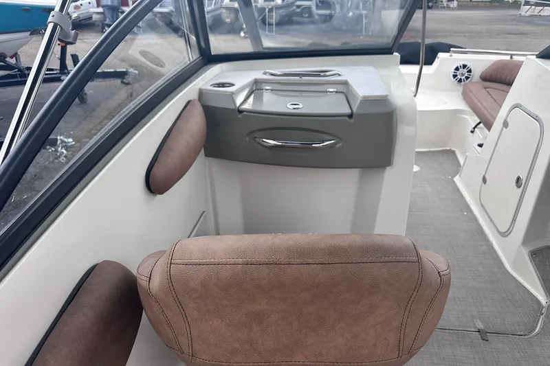 Slide: The Image of Interior of a 2022 Stingray 201 DC boat, featuring brown seating and a compact console. - 16