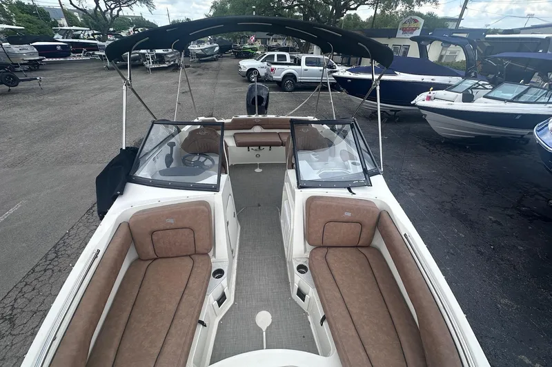 Slide: The Image of 2022 Stingray 201 DC boat with tan seating and black canopy in a marina. - 18