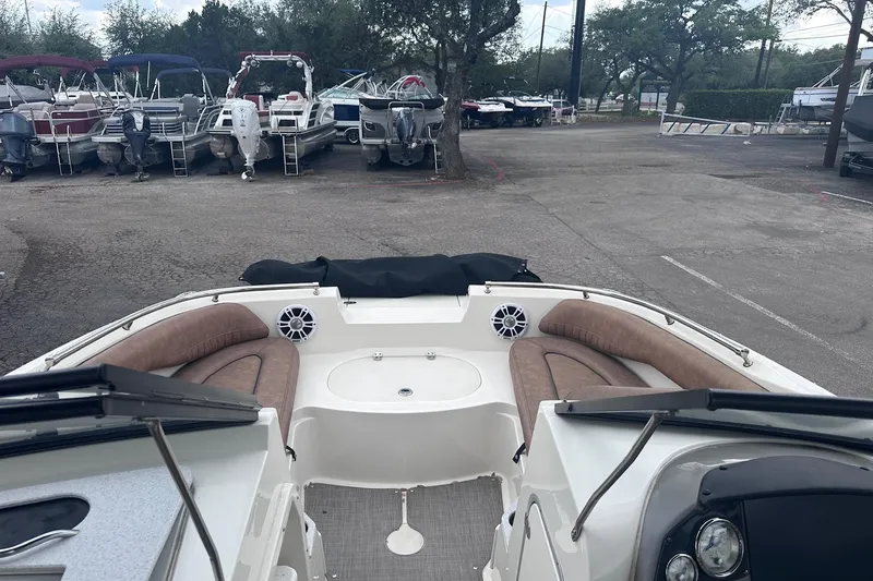 Slide: The Image of 2022 Stingray 201 DC boat interior with seating, parked among other boats. - 20