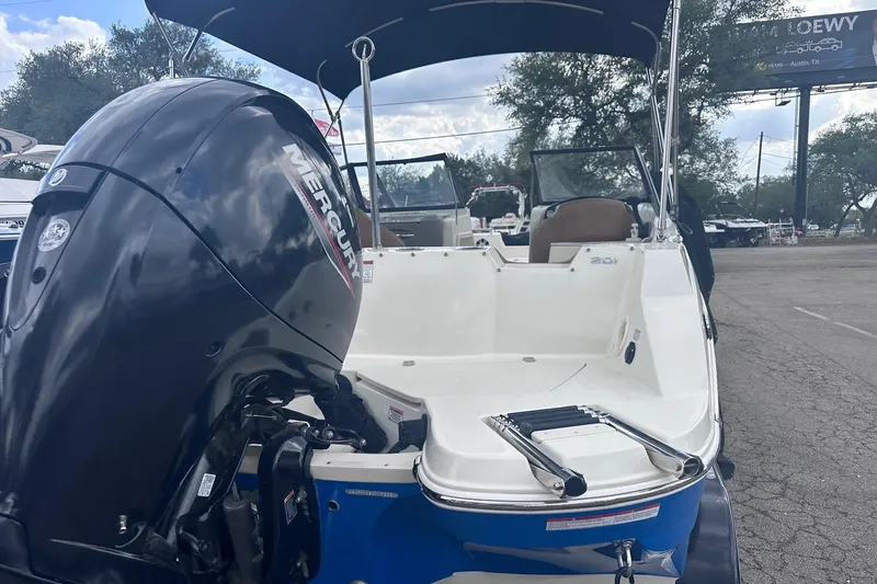 Slide: The Image of 2022 Stingray 201 DC boat with Mercury outboard motor, parked outdoors. - 5