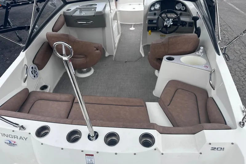 Slide: The Image of 2022 Stingray 201 DC boat interior with brown seating, steering wheel, and cup holders. - 6